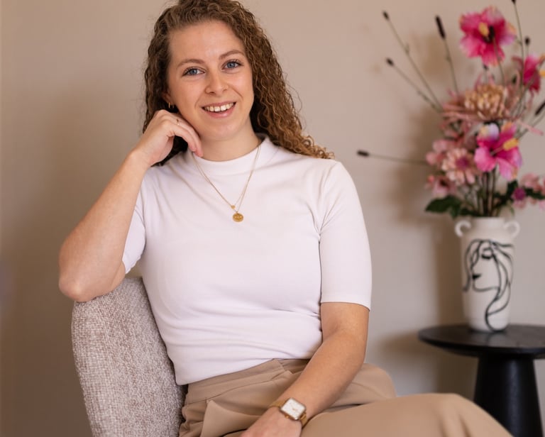 a woman, the writher, sitting in a chair with a flower in the background