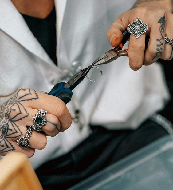 Un joyero tatuado utiliza pinzas especializadas para joyería artesanal