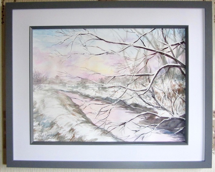 Pale sunrise colours reflected on snow and water; snow-laden tree branches cross river. Watercolours
