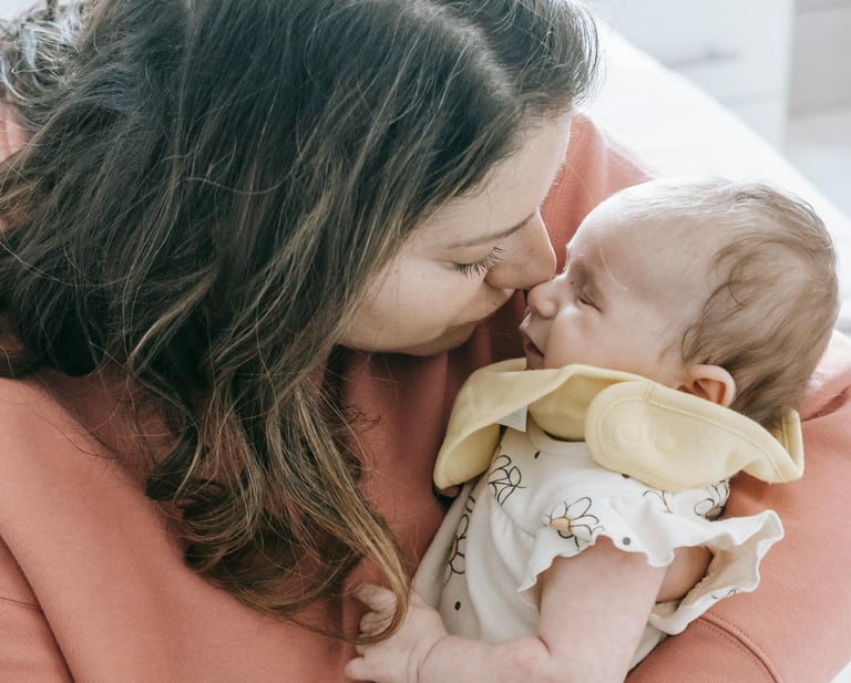 A mom holding her baby with their faces touching lovingly