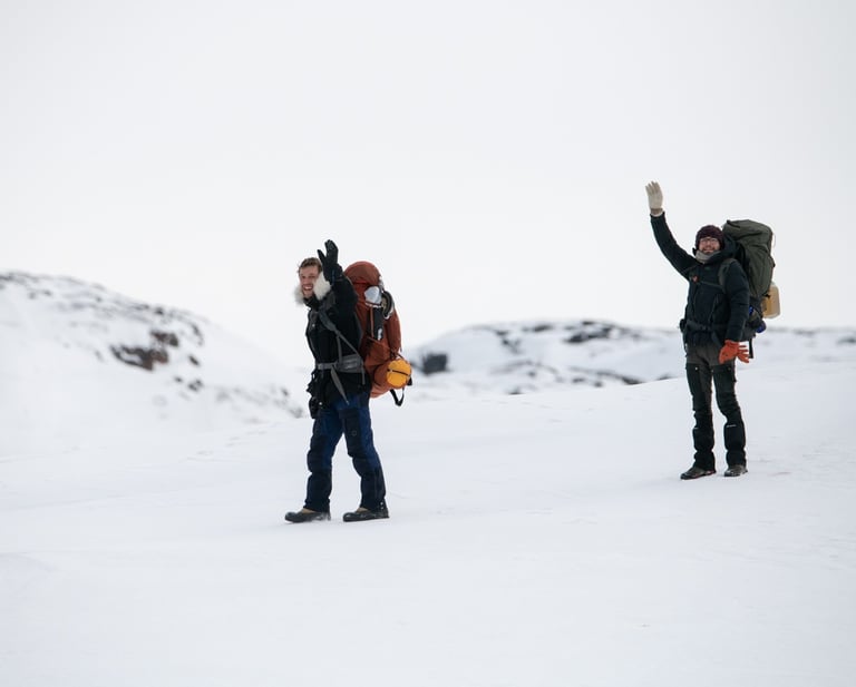 Deux randonneurs avec des sacs à dos font signe de la main en traversant un paysage hivernal enneigé