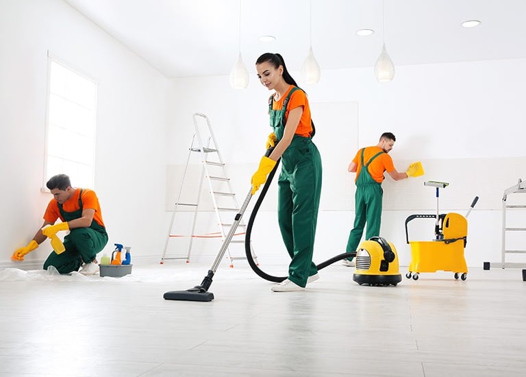 a woman in green overalls cleaning a room