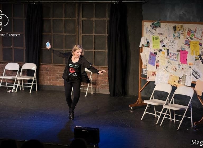 a woman Amy Cave in a black top tap dancing on stage in a play.