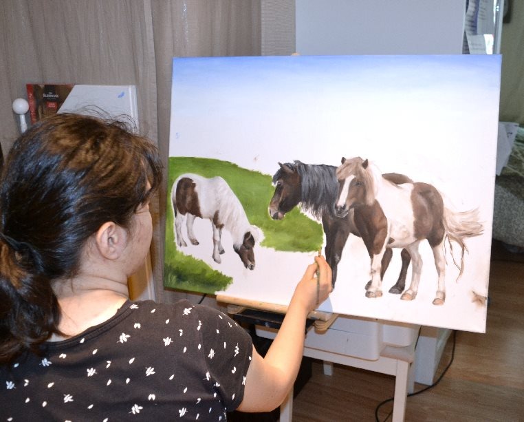 a woman is painting a picture of ponies