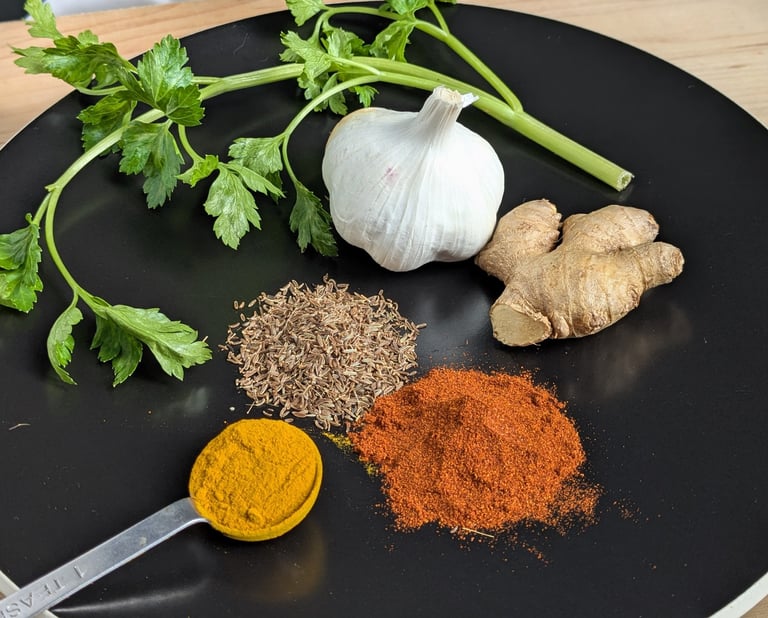 Fresh aromatics prepared for cooking, including ginger, garlic, spices and herbs