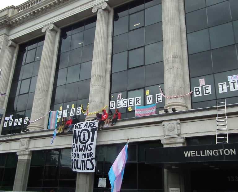 Activists sitting on top of NHS England offices with a banner "we are not prawns for your politics"