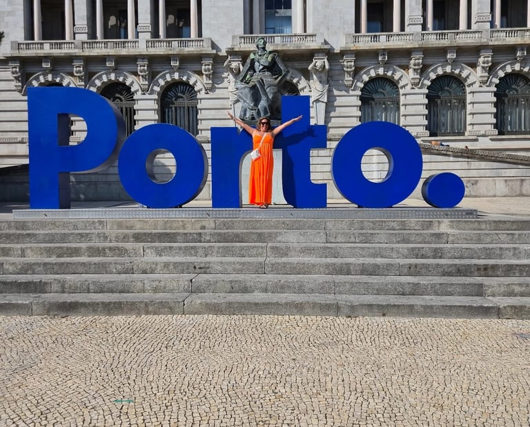 Una mujer con un vestido naranja posa junto al letrero azul de Porto frente al Ayuntamiento de Portu