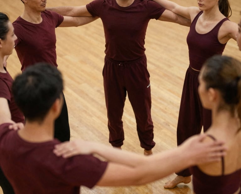 Un grupo de bailarines contemporáneos vestidos de color burdeos, de pie en círculo y con los brazos 