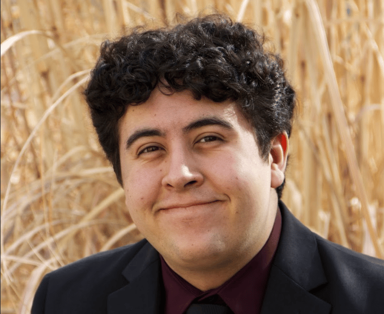 Headshot of Gregg in a black suit.