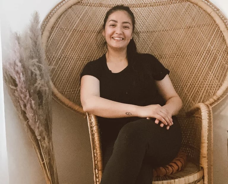 Smiling woman sitting in a wicker chair.
