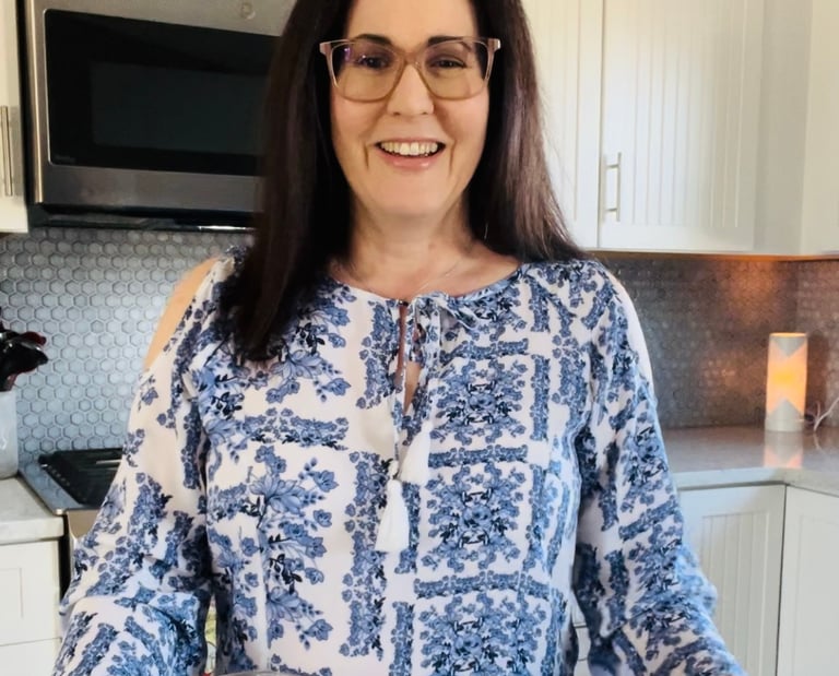 Woman standing in a kitchen with a plate of food and smoothie.