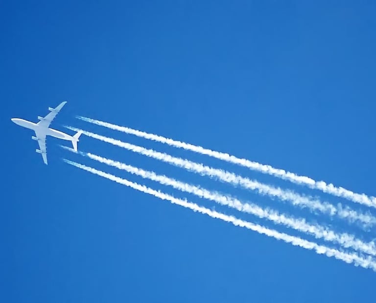 White passenger jet airplane flying through a clear blue sky leaving long white vapor contrails.