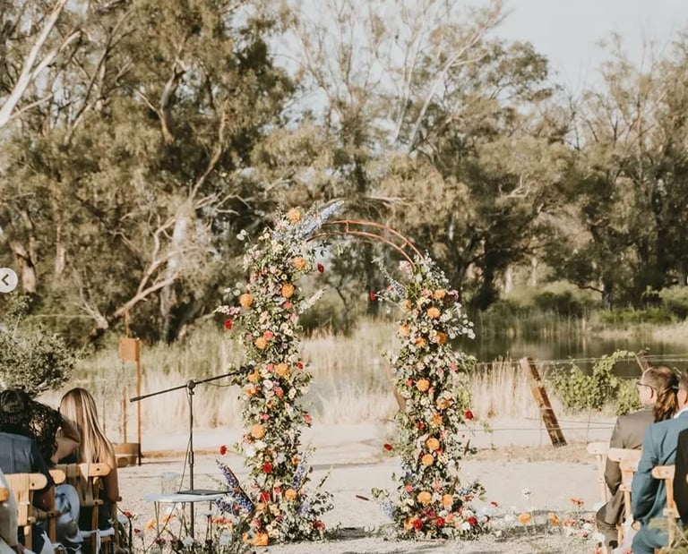 Arco floral decorando ceremonia en jardín natural.