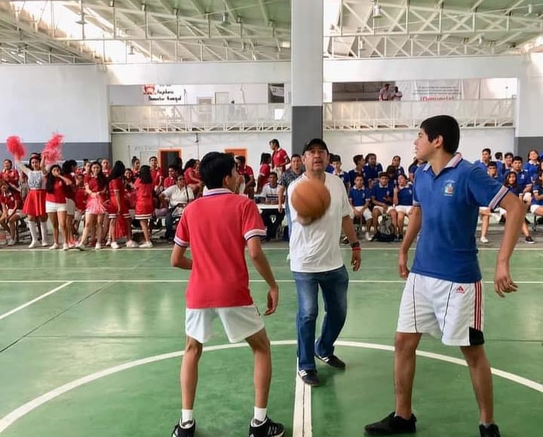 Alumnos jugando un partido de baloncesto en una competencia de rojos contra azules