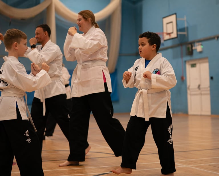 Students in white uniforms practicing martial arts techniques during a Choi Kwang Do class.