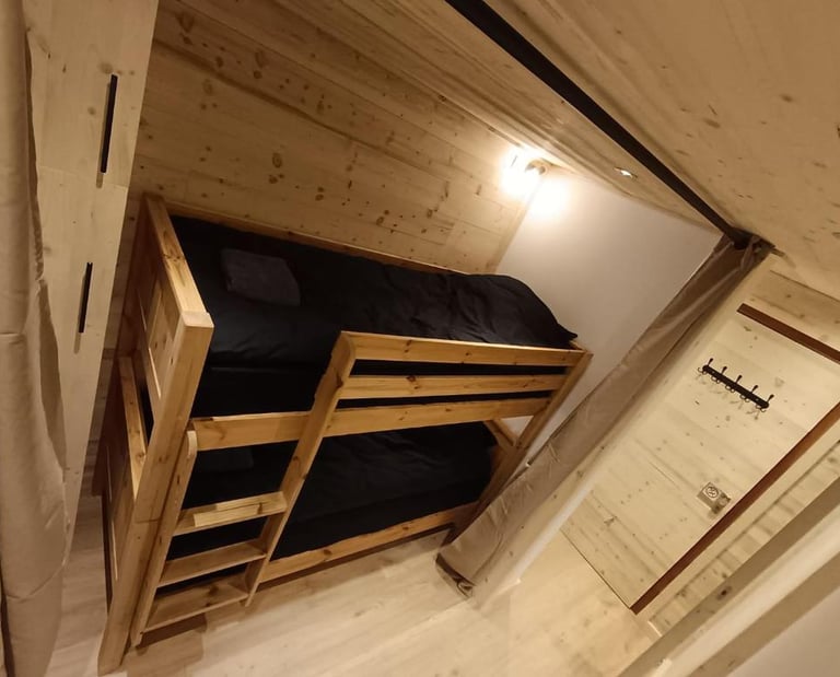 Bunk bed sleeping area in a cozy Val Thorens ski apartment with warm alpine wood interior.