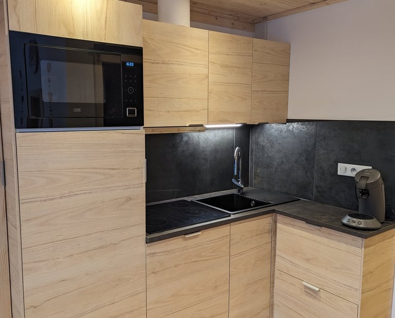 Fully equipped kitchen with oven, microwave combo and alpine wood interiors inside a Val Thorens ski apartment