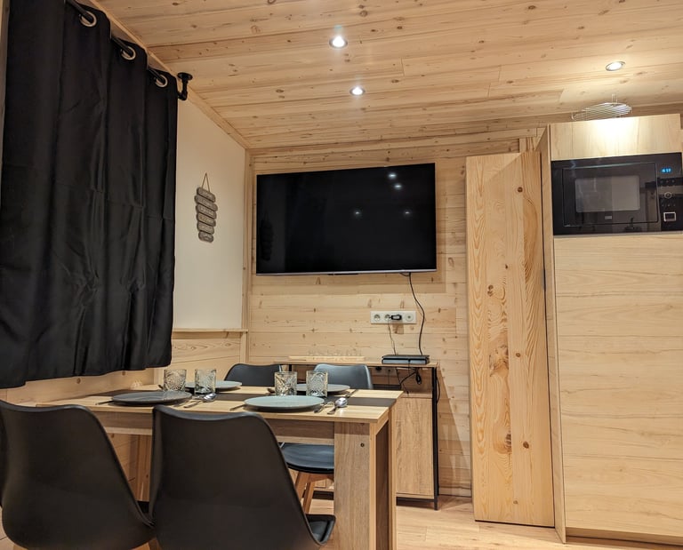 Dining and entertainment area inside a ski-in ski-out apartment with TV and warm wood interior