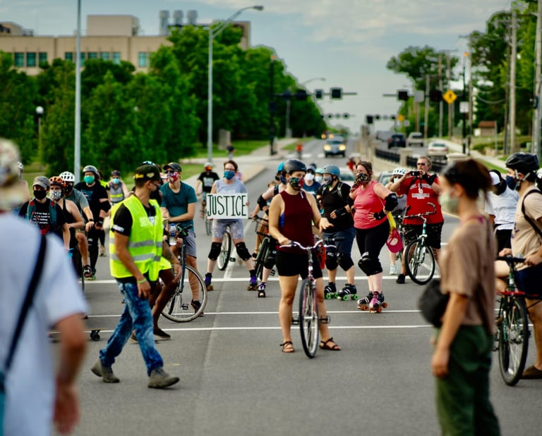 Bikers stopped on a road, with one holding a sign that reads "Justice"