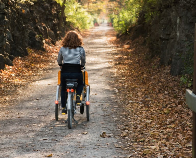 A person pedaling our "Giving Rides Bike" on a gravel trail