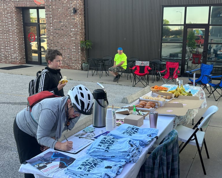 Mayor Barbara Buffaloe, wearing a bike helmet, filling out her name, at a table with pastries