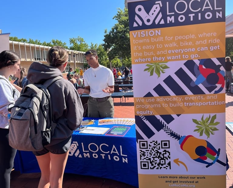 Local Motion table with a staff member talking to the public