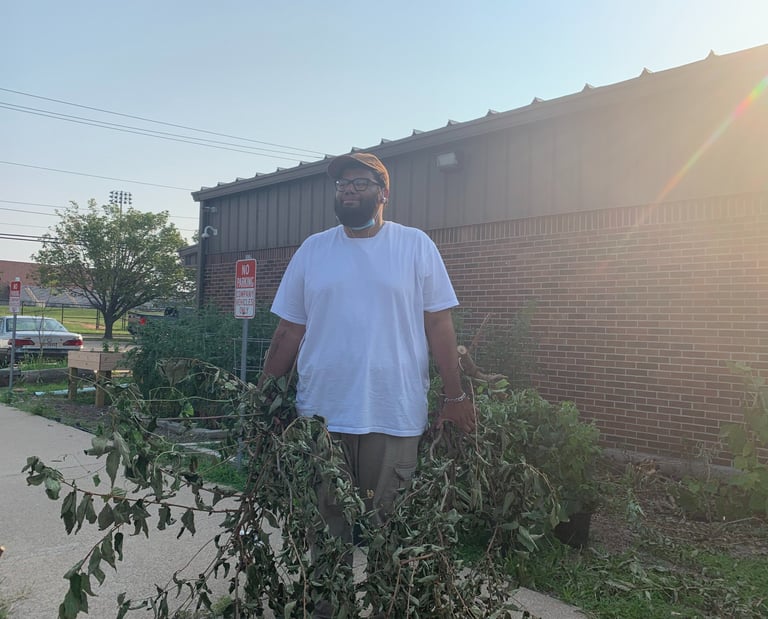 Headshot of Matthia Rickets holding some greenery he cut down