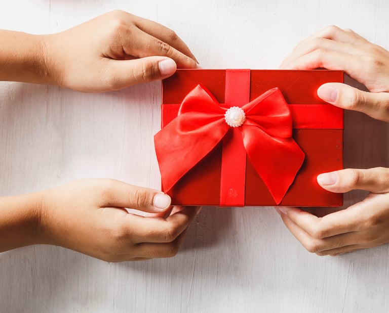 two hands holding a red gift box with a bow