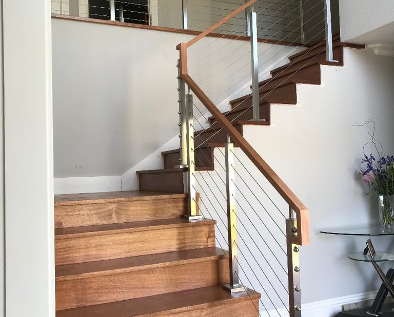 a staircase with a glass railing and a table with a vase of flowers