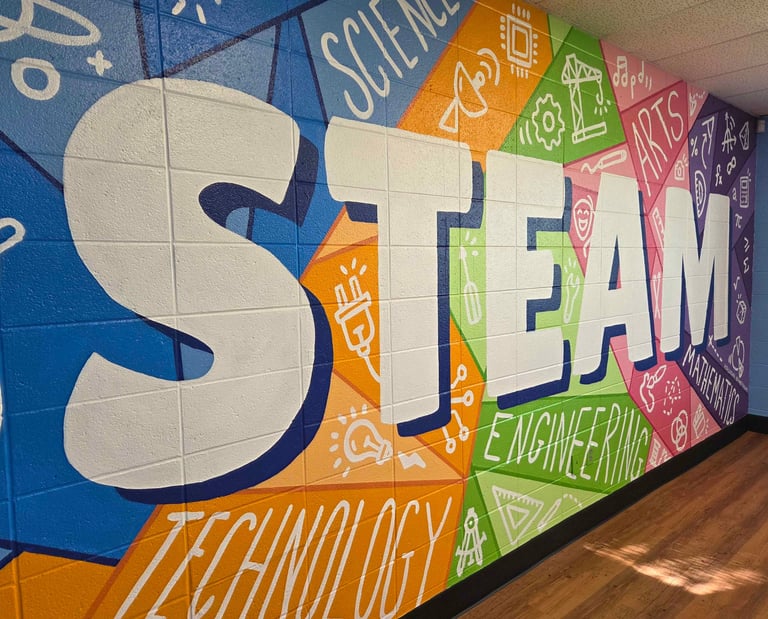 A colorful STEAM education mural on a brick wall featuring science, technology, engineering, arts, and math icons.