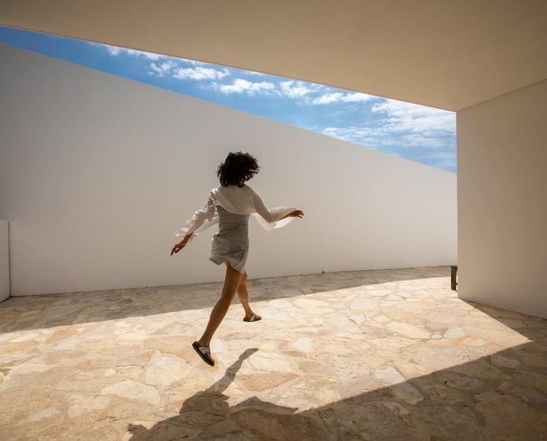 a woman in a white shirt and skirt jumping on a tiled floor in an architect house