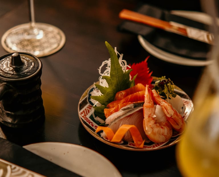 Fresh sashimi platter with salmon and prawns served on a ceramic plate with Japanese cocktails.