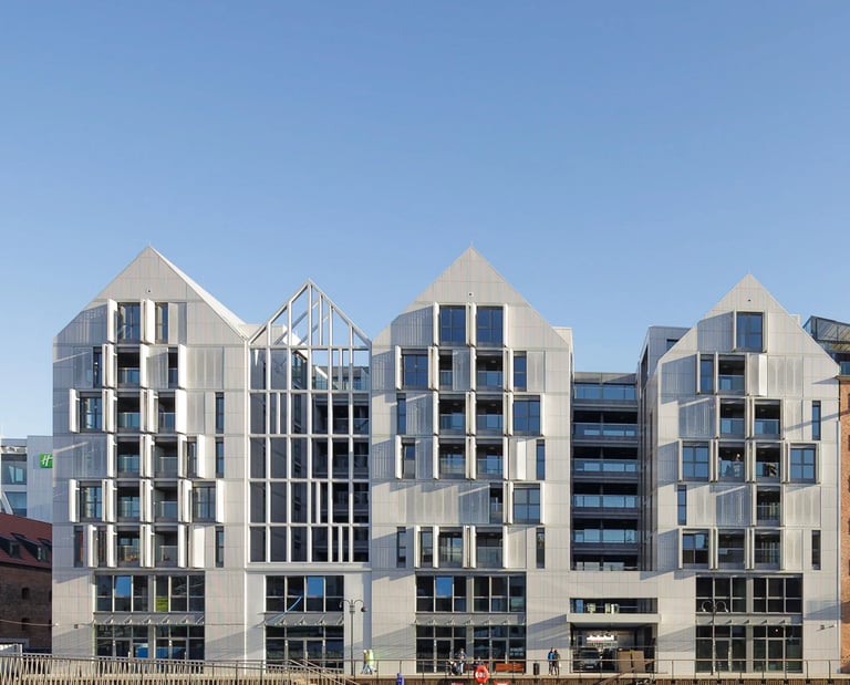 Nowoczesny budynek nad wodą z przeszkleniami i dwuspadowymi dachami