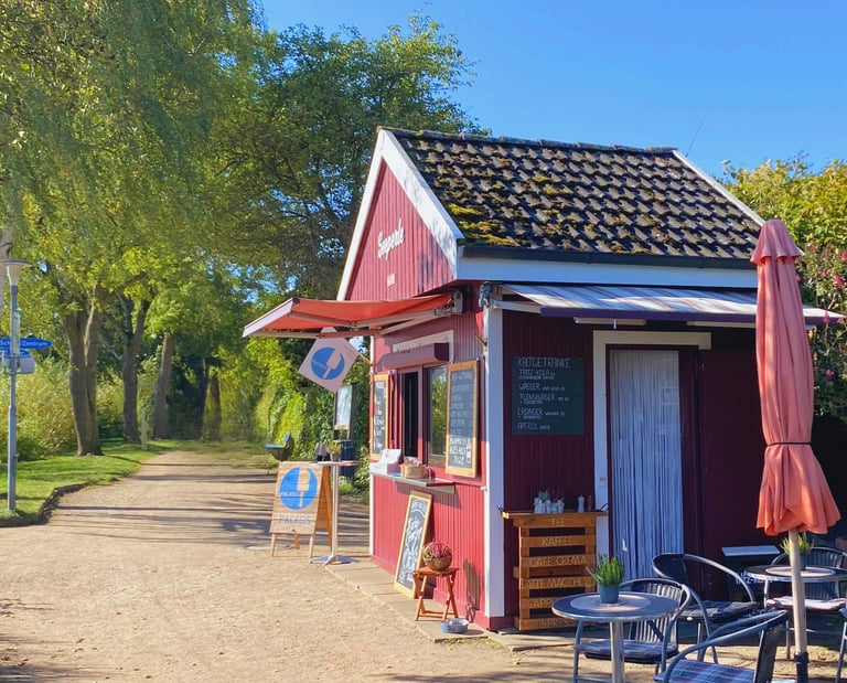 Der kleine Imbiss "Seeperle" am Plöner See mit Sonnenschein und Blick auf den Wanderweg