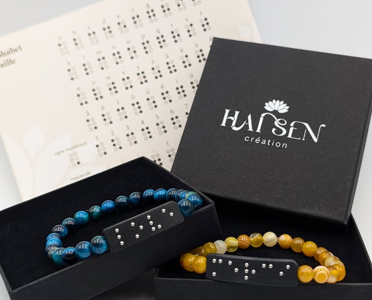 Bracelets perles avec plaques en braille, dans un écrin noire accompagné d'un alphabet braille.