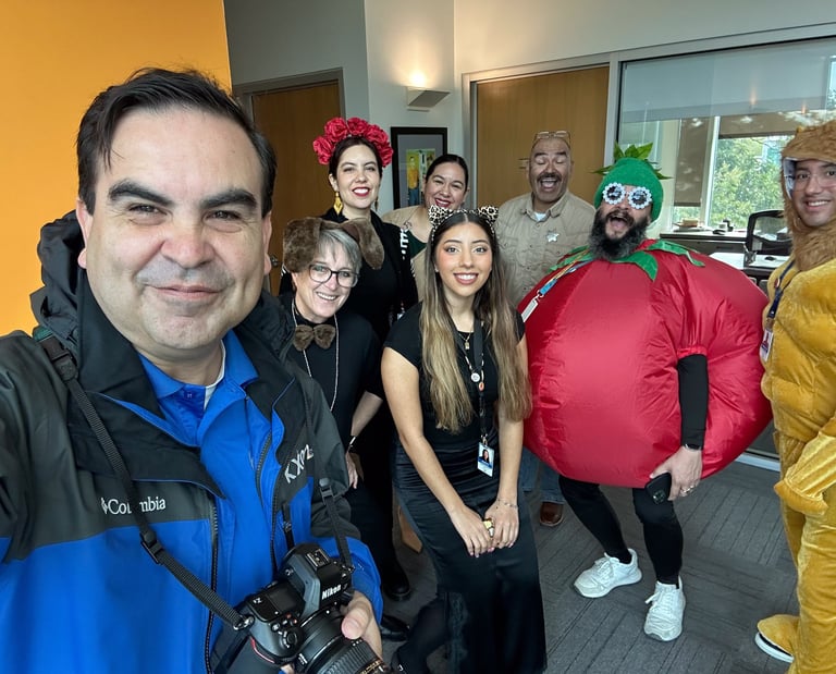 Francisco holds a camera, smiling with Southwest Key’s creative team in festive, fun costumes.