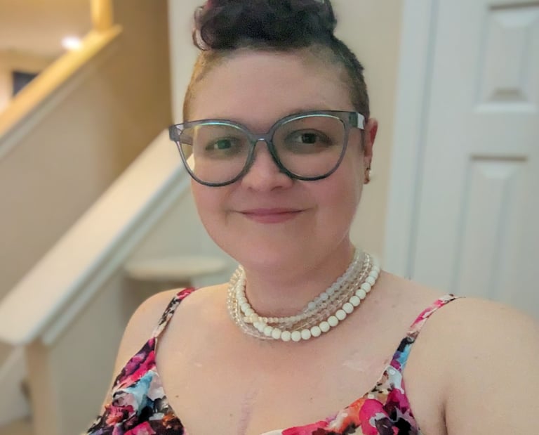 Picture of Megan, a smiling woman with a blue mohawk and pearls.