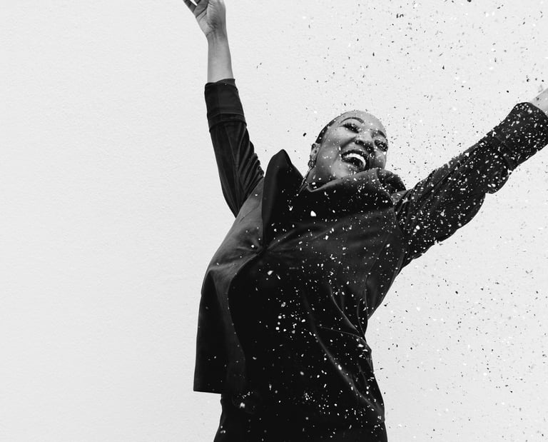 a woman in a black dress celebrating with confetti, black and white