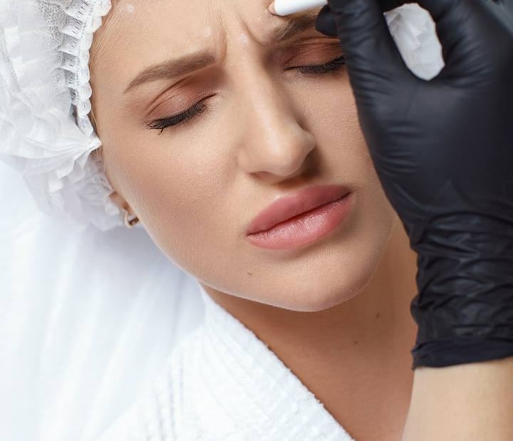 Cosmetic professional marking a patient's forehead for Botox or anti-aging facial injections.