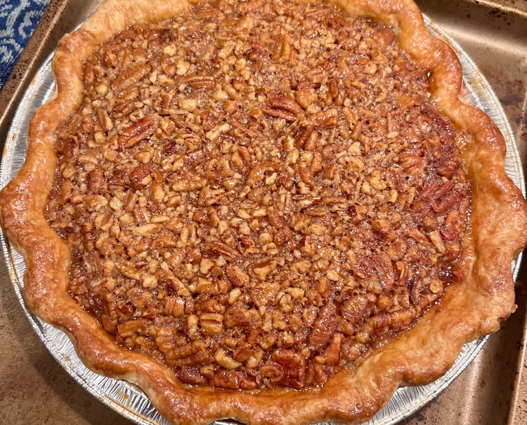 Freshly baked homemade pecan pie with a flaky golden brown crust on a baking sheet.