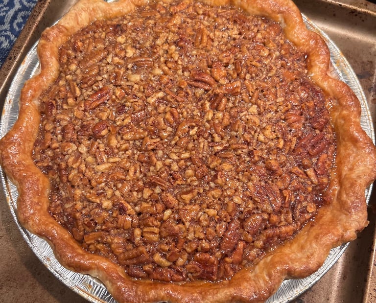 Freshly baked homemade pecan pie with a flaky golden brown crust and chopped nut filling.