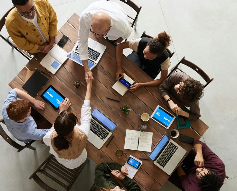 a group of people sitting around a table with laptops