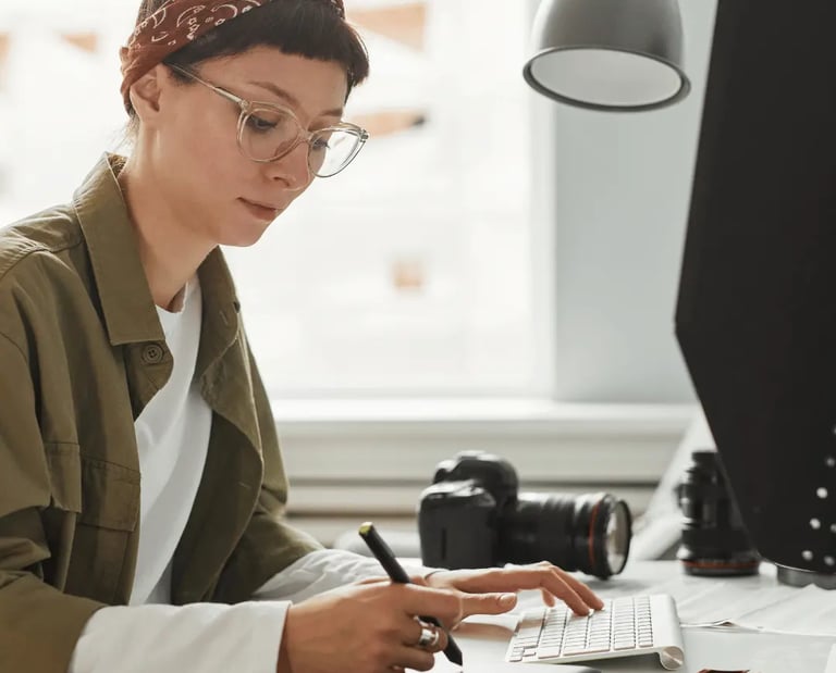 Real estate photo editor working on listing images at a desk with camera gear