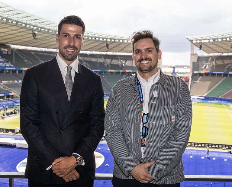 Sami Khedira (ex German footballer) and Tim Dougill posing for a photo in front of Berlin Stadium. 