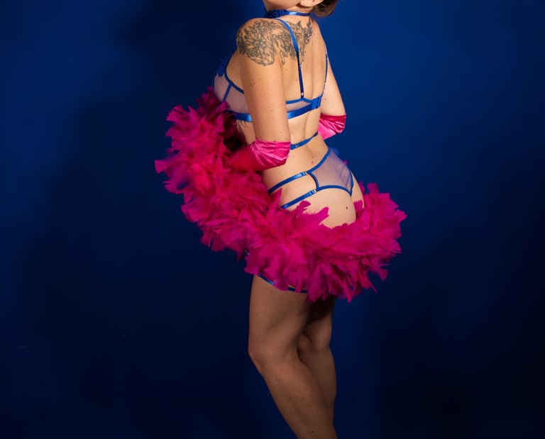 Pin up joyeuse en lingerie bleue avec un boa en plumes rose, qui sourie.