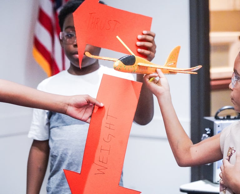 a young girl is holding a glider while other children hold force vectors lift drag thrust and weight
