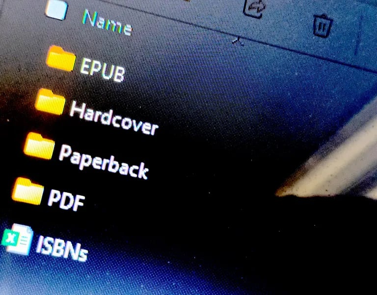 Close-up of a computer screen showing folders labeled EPUB, Hardcover, Paperback, and PDF