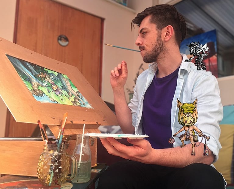 A handsome young male artist with dark hair and blue shirt sits at his easel of fantasy art