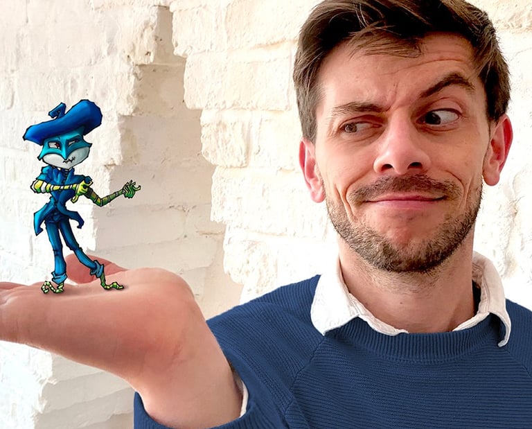 Young handsome gay male artist wearing a blue jumper holds one of his fantasy art figures.