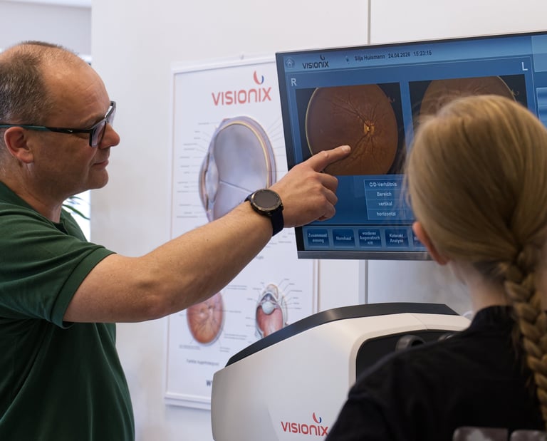 Optometrist pointing to retinal scan results on a Visionix monitor during an eye exam.